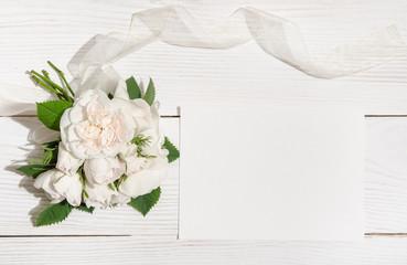 bunch of white roses on white table with empty card for you text
