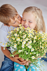 Happy kids with camomile bouquet at home