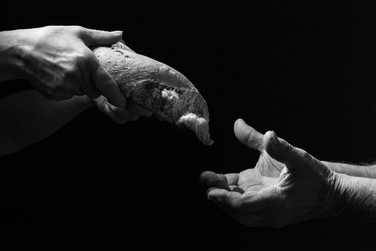 Mano di donna dona pagnotta di pane a un povero senzatetto. Concetto di povert&agrave; , emarginazione , fame nel mondo 