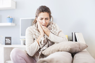 Portrait of young woman sitting in the living room with hard toothache,shallow depth of field