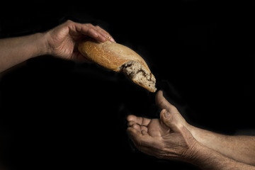 Mano di donna dona pagnotta di pane a un povero senzatetto. Concetto di povertà , emarginazione ,...