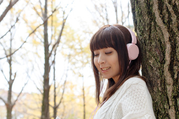 Fototapeta premium 紅葉した森で音楽を聴く女性