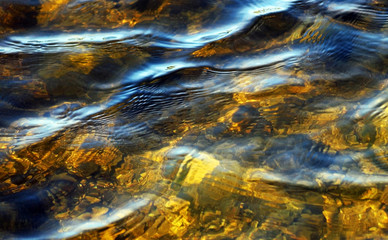 Obraz na płótnie Canvas Soft rippling waters in shades of gold with light reflecting on surface 
