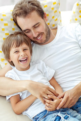 Happy father with son lying on the sofa