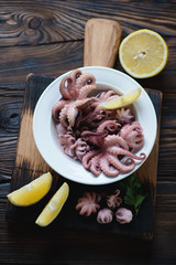 Glass plate with baby octopuses and lemon, high angle view