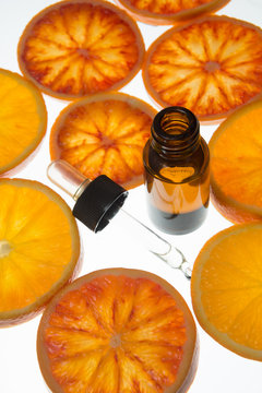 orange essential oil in amber bottle with blood orange slices 