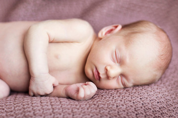 adorable little newborn boy sleeping on the brown blanket