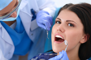 Woman dentist working at her patients teeth