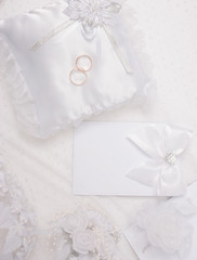 The wedding invitation with wedding rings and a bouquet of the bride on a white background