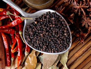 Black pepper in a spoon and  bay leaf