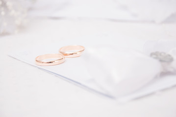 The wedding invitation with wedding rings and a bouquet of the bride on a white background