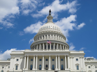The US Capitol Building in Washington, DC with blue, cloudy sky background.