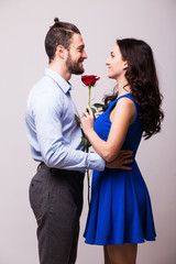 Smiling caucasian woman hugging her boyfriend and holding the rose.