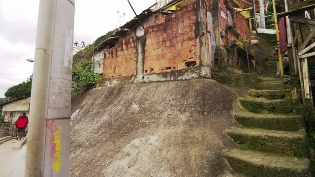 Slow motion shot of shanties and a walking man at a favela in Rio de Janeiro, Brazil