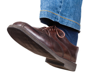 step of male left leg in jeans and brown shoe