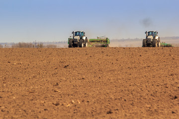 Fototapeta premium panorama of two tractors sowing in field