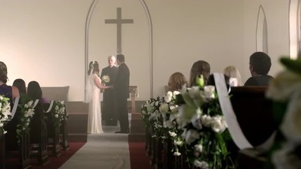 Bride and groom at the front of a chapel with a preacher.