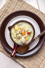 Homemade cauliflower soup in a brown bowl.
