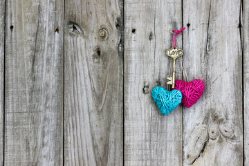 Key and hearts hanging on rustic wood door