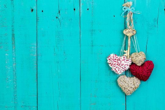 Key and hearts hanging on rustic teal blue wood door