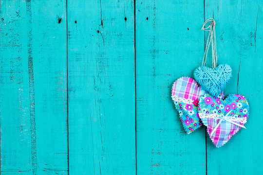 Pink and turquoise hearts hanging on rustic wooden background