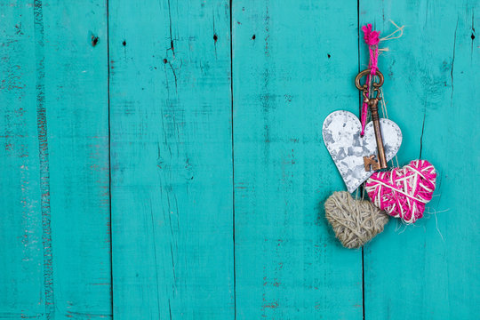 Hearts and key hanging on rustic teal blue wood door