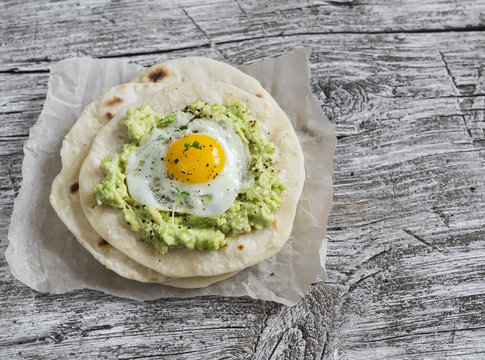 Homemade tortilla with mashed avocado and a fried quail egg. Delicious snack, healthy food