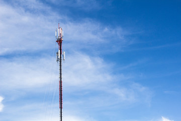 Obraz premium Red and white tower of communications with antennas under blue sky and clouds
