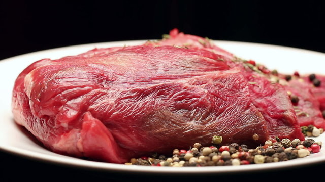 Fresh raw beef meat with peppercorns ready to grill, rotating