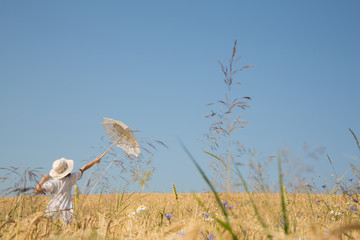 Unbeschwertheit, Hoffnung und Freiheit Konzept. Junge Frau in einem Weizenfeld bei blauem Himmel und Horizont.