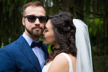 Beautiful bride leaning in to kiss handsome confident groom in s