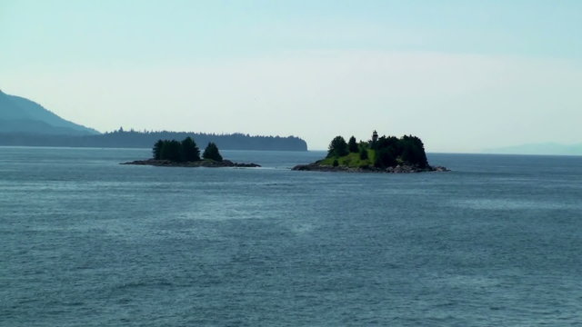 Traveling view of a small island with a lighthouse near Juneau, AK.