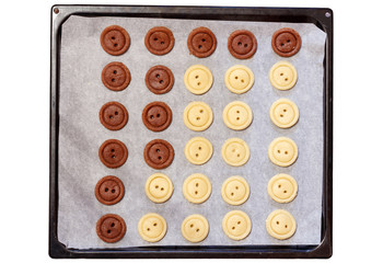 Raw dough. Yellow and brown cookies buttons on sheet pan. Cooking. Isolated white background