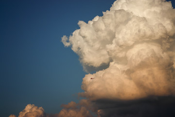 Ein Hubschrauber fliegt vor einer riesigen Gewitterwolke, die das drohende Unwetter ankündigt. 