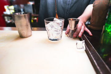 Fototapeta na wymiar Bartender preparing a cocktail. Glass with ice on the bar