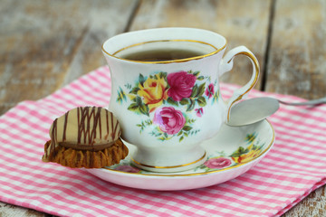 Tea in colorful vintage porcelain cup with chocolate and toffee crunchy cookie
