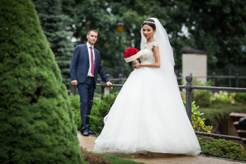 Newlywed valentynes posing in a romantic european park with rose