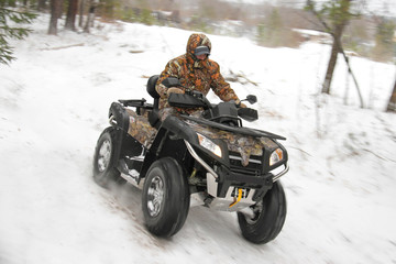 man driving a quad bike in the winter forest