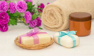 Obraz na płótnie Canvas Two pieces of soap with a basket with a bows , flowers , towel a