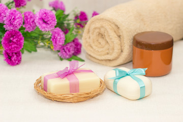 Obraz na płótnie Canvas Two pieces of soap with a basket with a bows , flowers , towel a