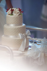 Delicious tiered white wedding cake decorated with roses and a r
