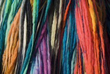 Close up on mixed colours of dyed wool hanging on a rail, for sale at the Green Gathering, Chepstow, Wales
