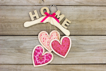 Pink fabric hearts and HOME hanging on hanger with wood background
