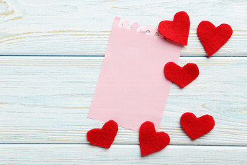Red hearts and sheet of blank paper on a blue wooden table