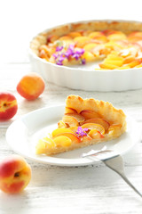 Slice of apricot pie on white wooden background