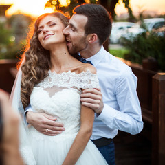 Romantic valentynes couple of newlyweds hugging at kissing at sunset near a wooden house closeup