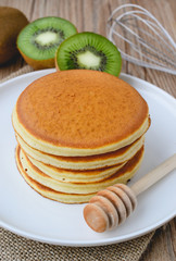 stack of pancake on white plate and sackcloth with kiwi slices o