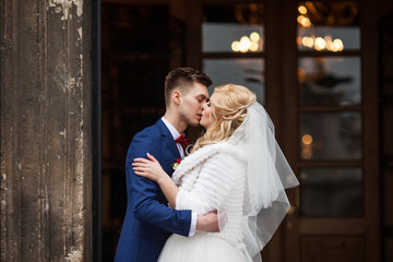 Handsome newlywed groom kissing happy bride outside church after