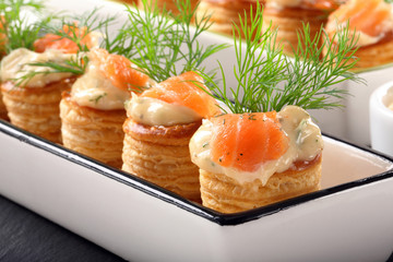 Appetizer puff pastry with dill dip and salmon on stone tray
