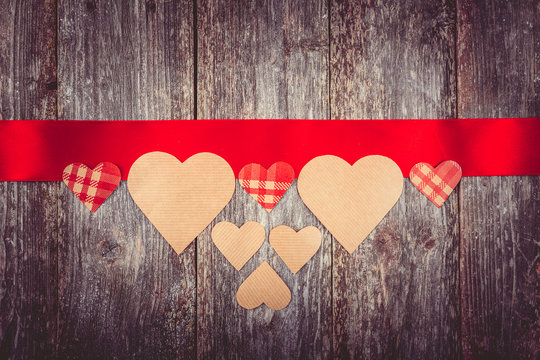 Valentines Day background - many hearts on red ribbon on wooden background. text space. Instagram color toning